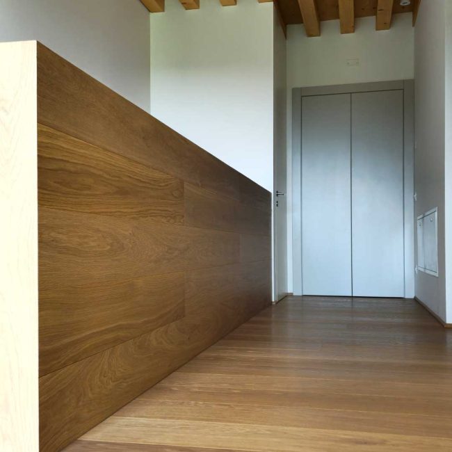 Pavimento in rovere naturale leggermente spazzolato e parapetto rivestito con le stesse tavole usate per il pavimento.