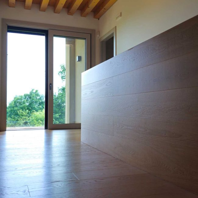 Pavimento in rovere naturale leggermente spazzolato e parapetto rivestito con le stesse tavole usate per il pavimento