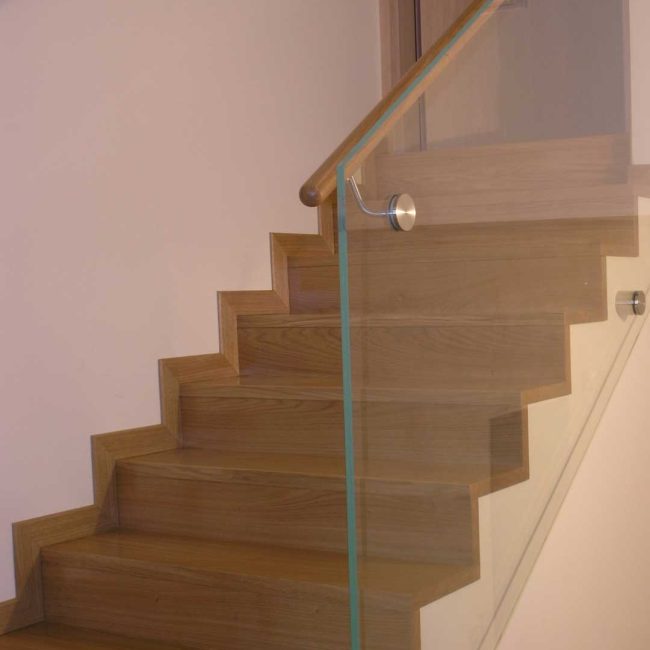 Scala in rovere e parapetto in vetro temperato.