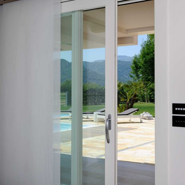 Porta esterna ad una anta fissa e una alzante scorrevole laccata con guida bassa incassata a pavimento, disponibile nella versione a taglio termico.