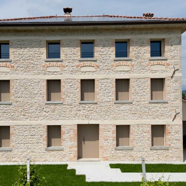 Facciata con scuri monoblocco a due ante laccati. Portoncino in legno bicolore.