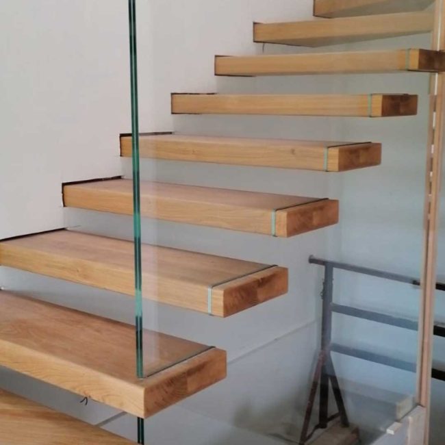 Scala con pedate in rovere. Parapetto in vetro trasparente temperato.